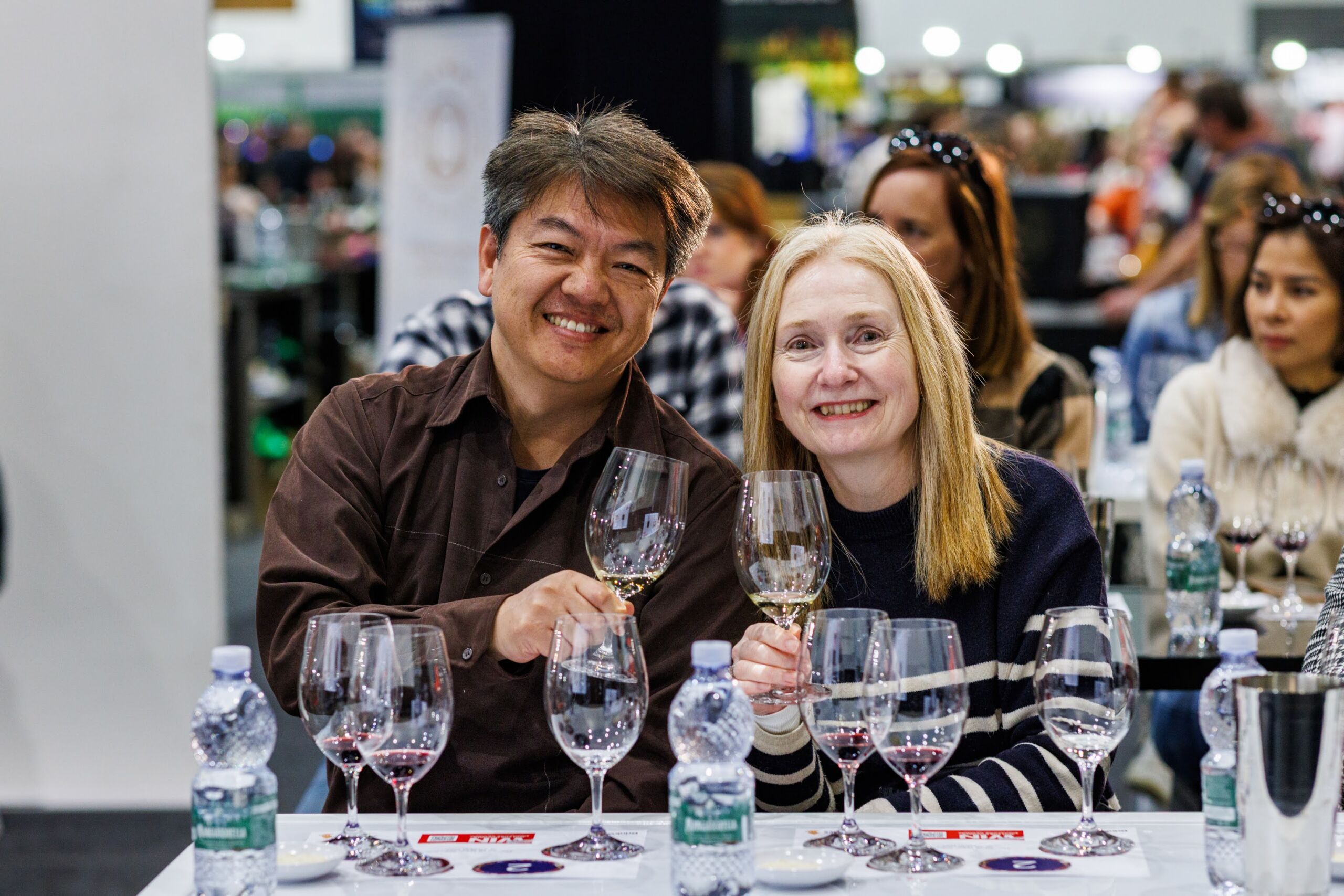 Man and woman smiling at the camera while holding glasses of wine during a Drinks Lab session at the Good Food & Wine Show.