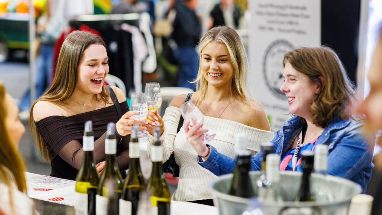 Three women cheering with tasting glasses at the Good Food & Wine Show