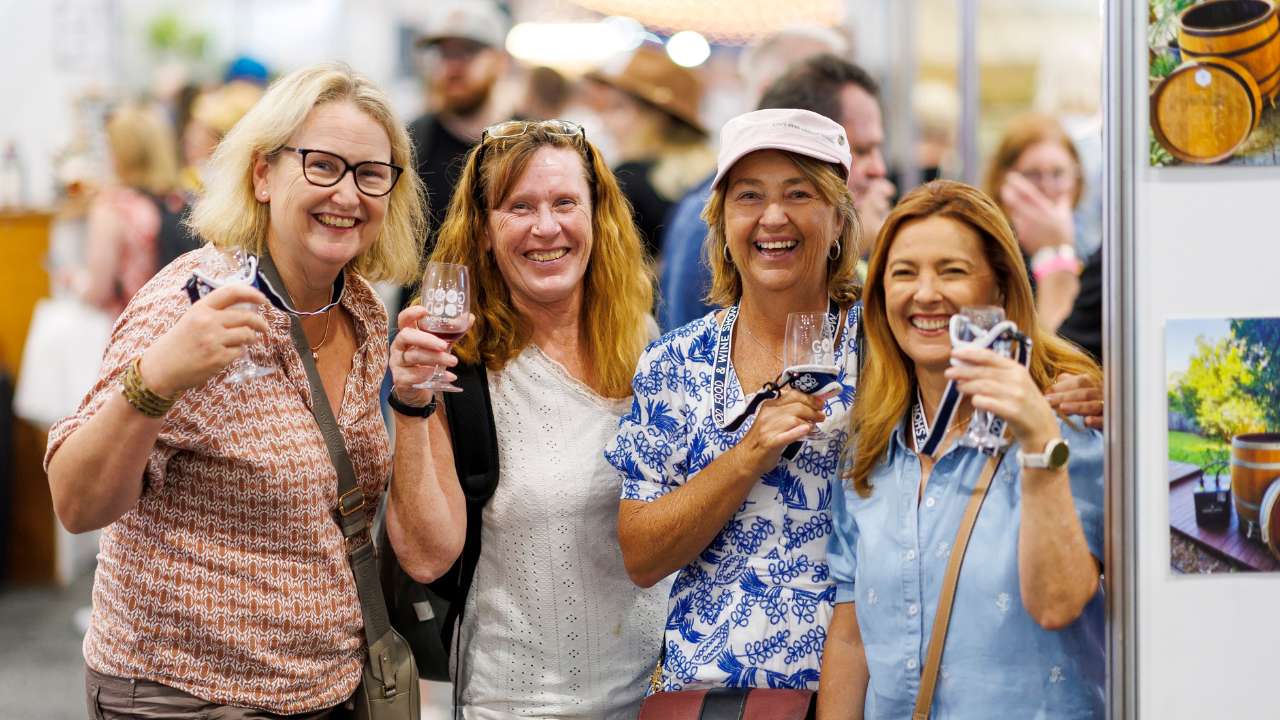Four women smiling at the camera with tasting glasses at the Good Food & Wine Show