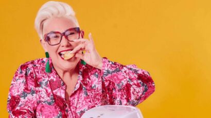 Celebrity chef Steph de Sousa smiling at the camera while playfully biting into a snack