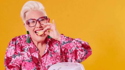 Celebrity chef Steph de Sousa smiling at the camera while playfully biting into a snack