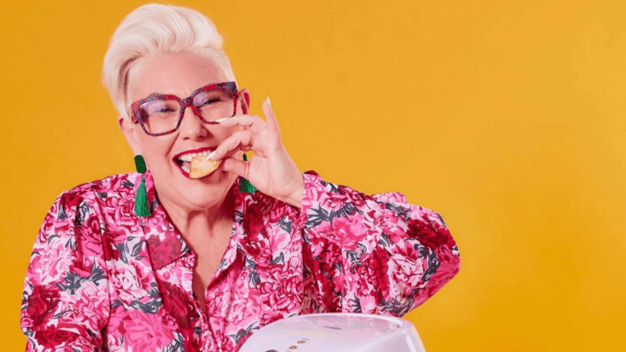 Celebrity chef Steph de Sousa smiling at the camera while playfully biting into a snack