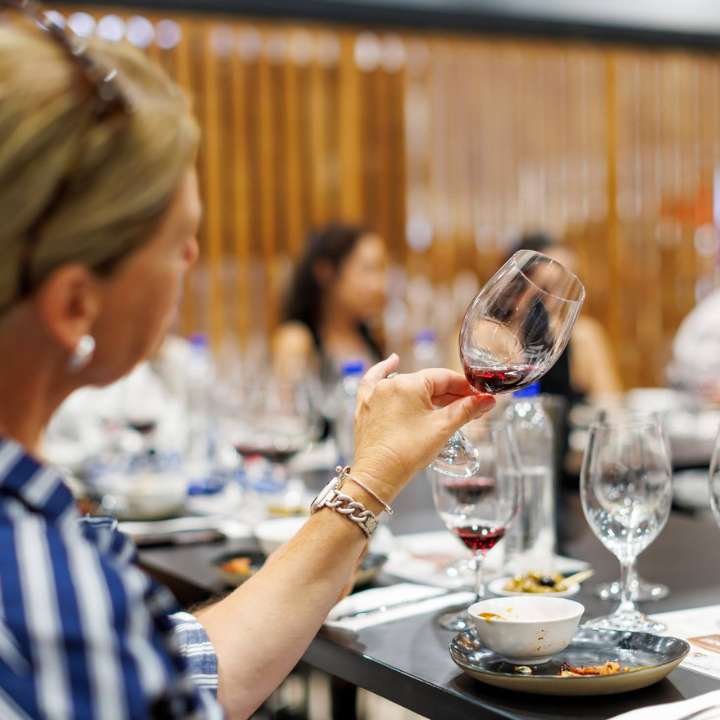Woman examining the colour of red wine in a tasting glass in the Wine Selectors Tasting Room at the Good Food & Wine Show