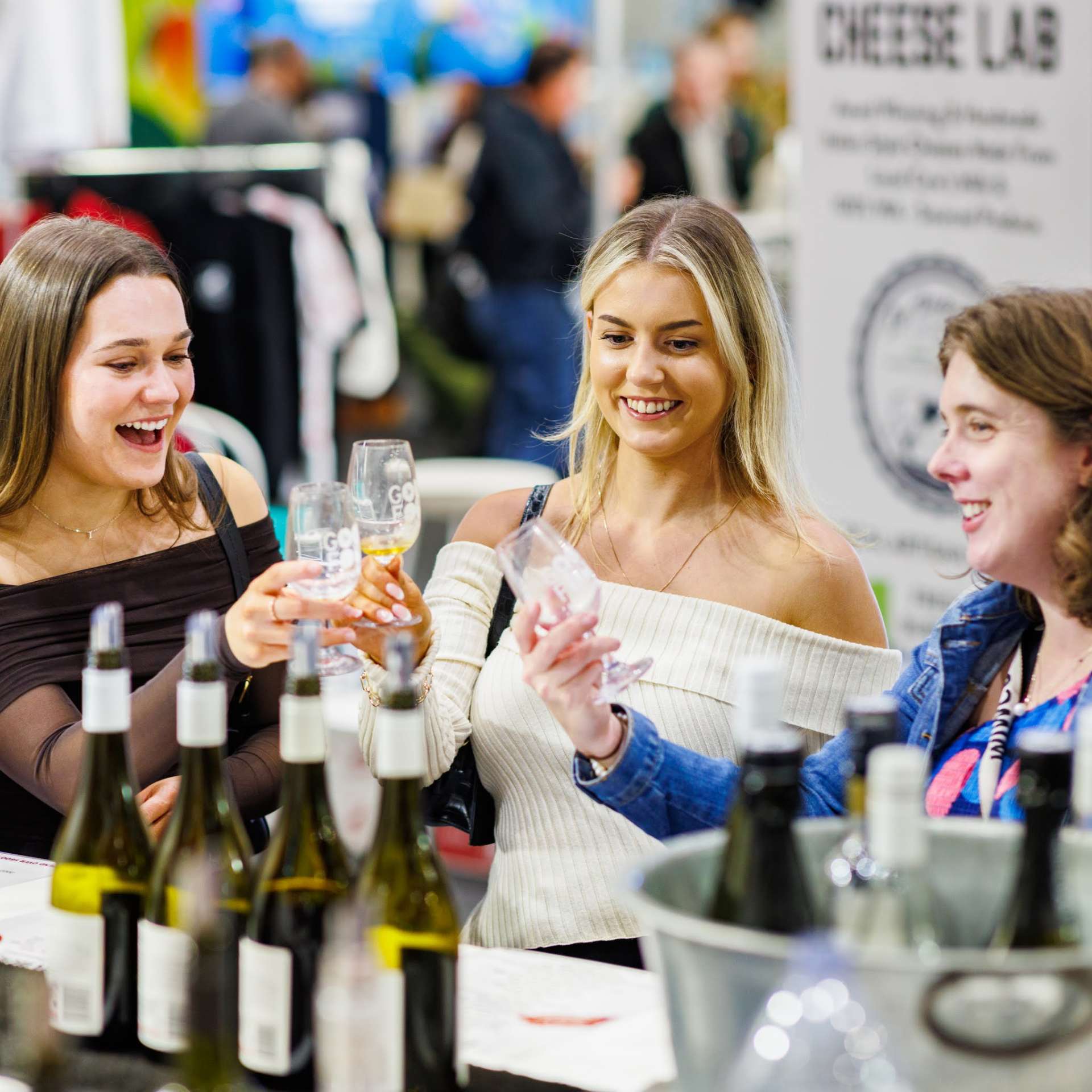 Three women holding tasting glasses for a pour at the Good Food & Wine Show