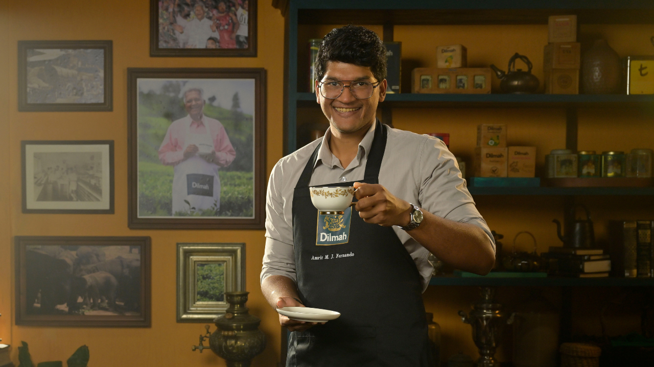 Amrit M. J. Fernando holding up a mug of Dilmah tea to the camera, showcasing the tea brand