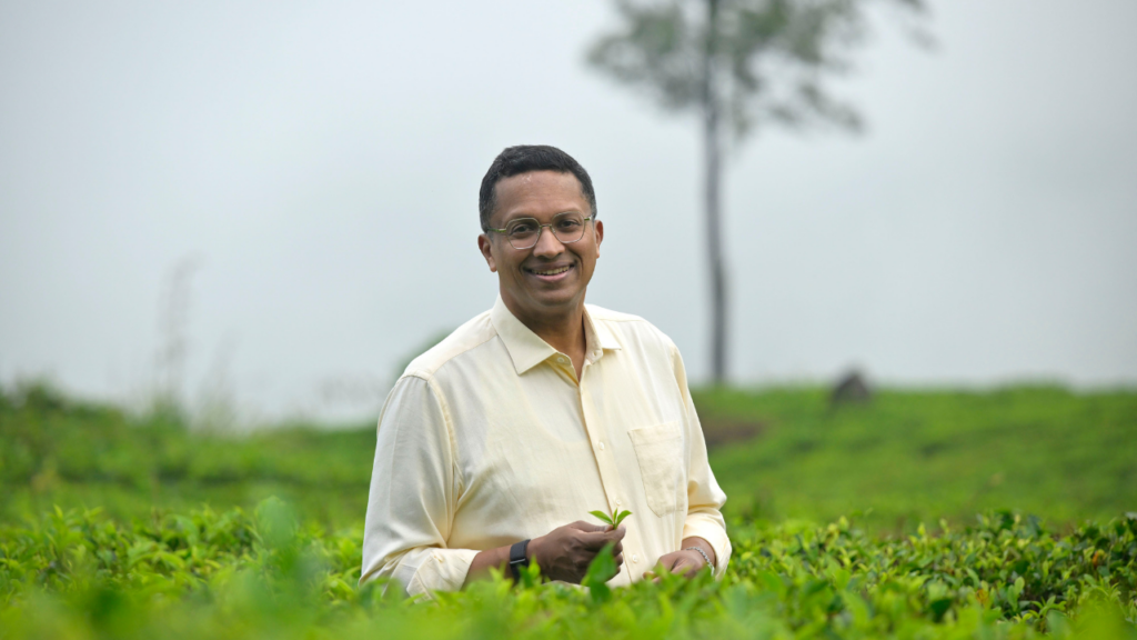 Dilhan C. Fernando, Chairman and CEO of Dilmah Tea, standing in a lush tea plantation in Sri Lanka