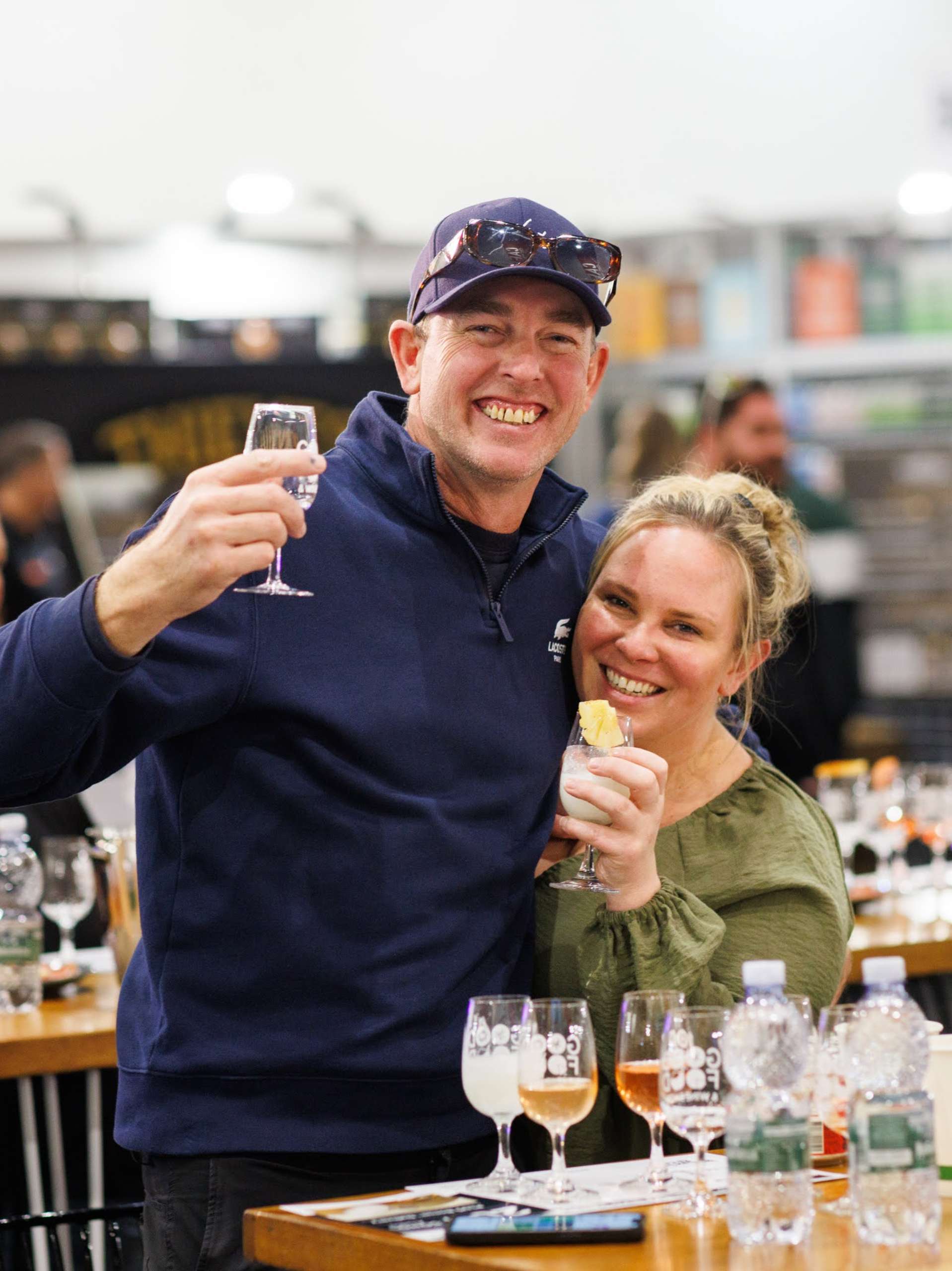 Man and woman smiling at the camera during the Spirit Lover Masterclass at the Good Food & Wine Show, seated at a tasting table with spirits glasses.