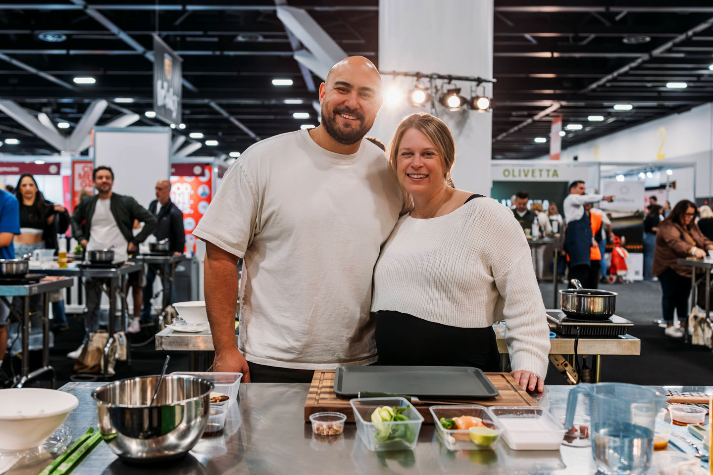 Couple smile, enjoying the cooking masterclass experiences at the Good Food & Wine Show.