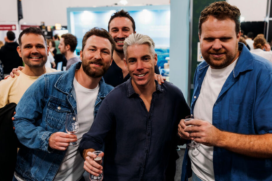 Five visitors raise their glasses and smile, enjoying the tasting experiences at the Good Food & Wine Show.
