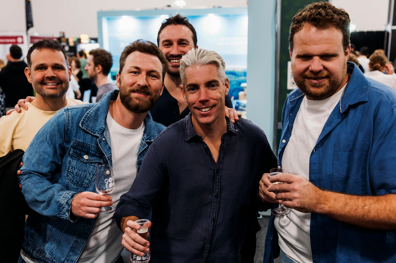 Five visitors raise their glasses and smile, enjoying the tasting experiences at the Good Food & Wine Show.