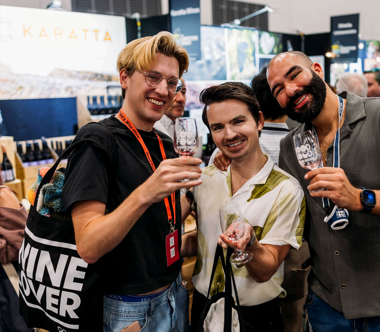 Three men toasting with wine glasses at the Good Food & Wine Show tasting session.